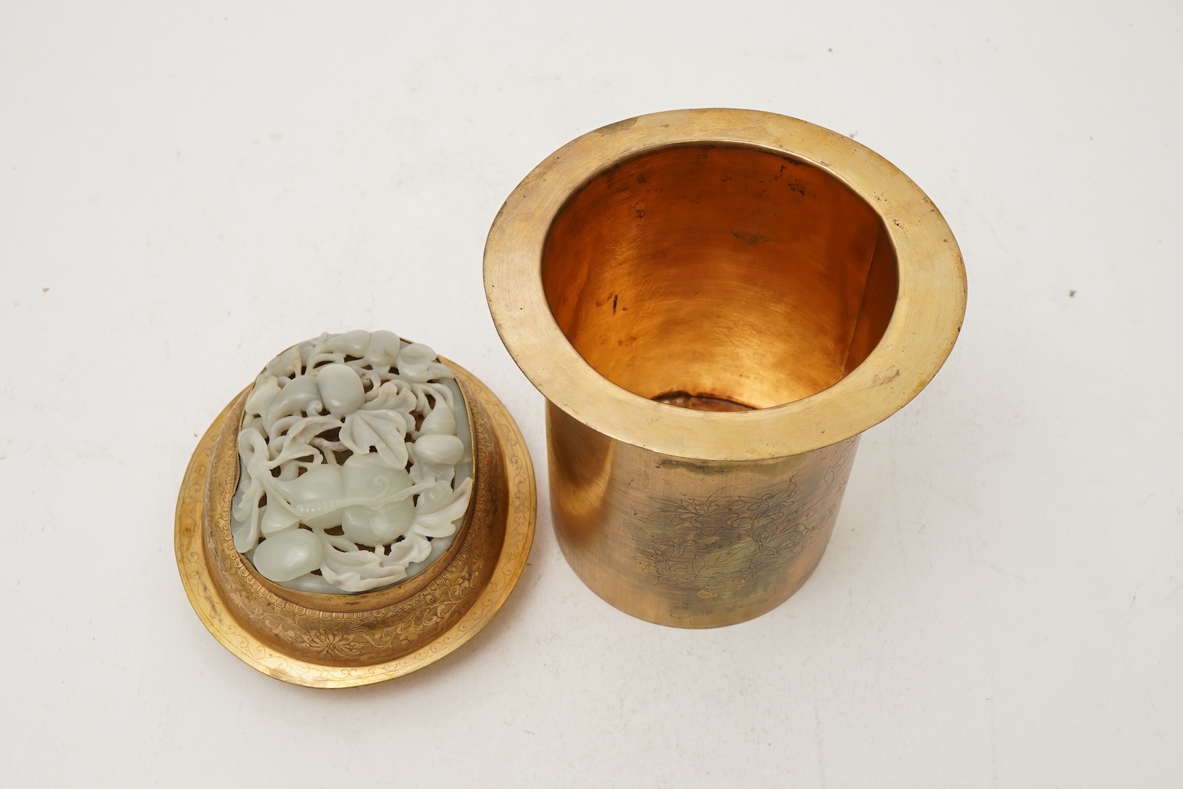 A Chinese pale celadon jade oval plaque, 17th/18th century, mounted on a late Qing gilt copper jar